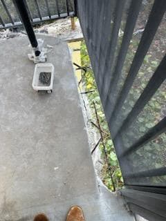 Initial assessment of balcony edge spalling damage showing deteriorated concrete at railing base in Key West