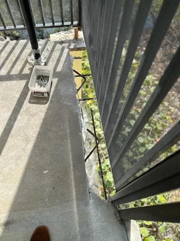 Close-up of spalling repair preparation with exposed rebar and fasteners on Key West balcony