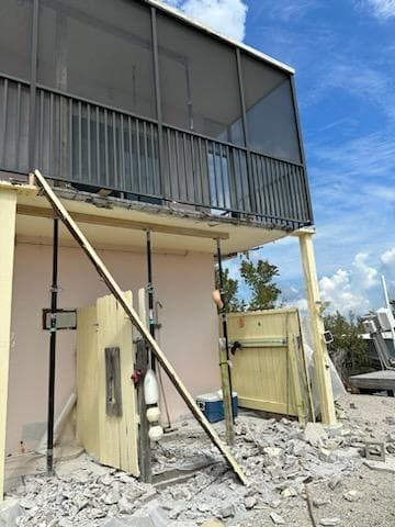 Two-story building exterior with temporary shoring posts supporting structure during major spalling repair in Key West